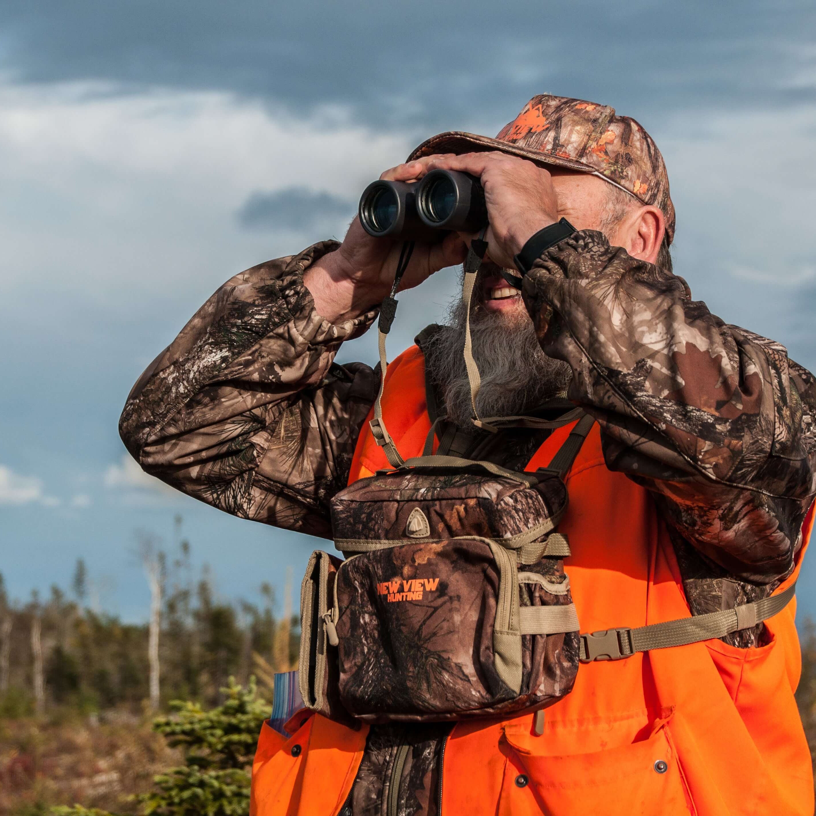 Hunter wearing a camo bino harness while glassing in the field