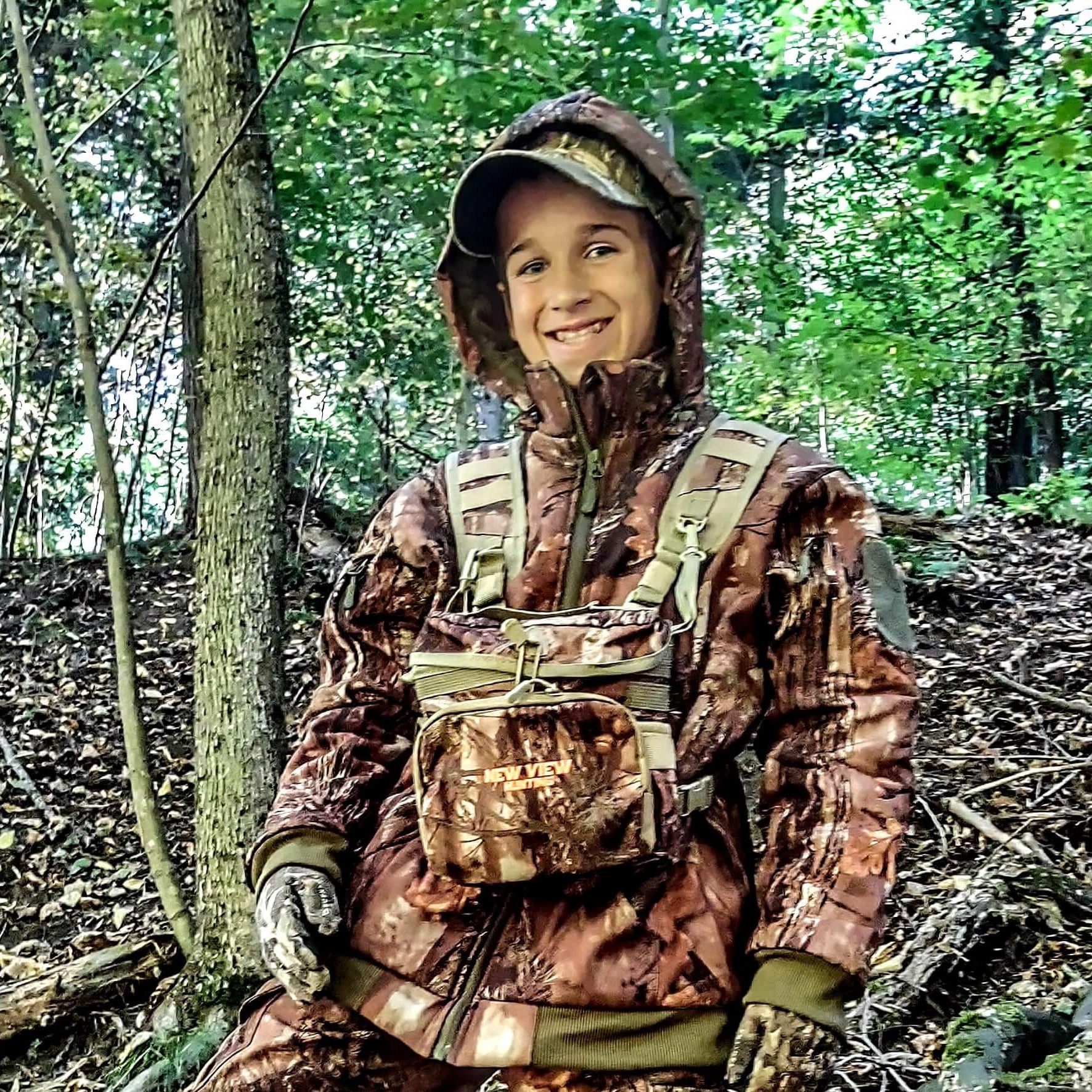 Young hunter wearing camouflage hunting clothing in woodland