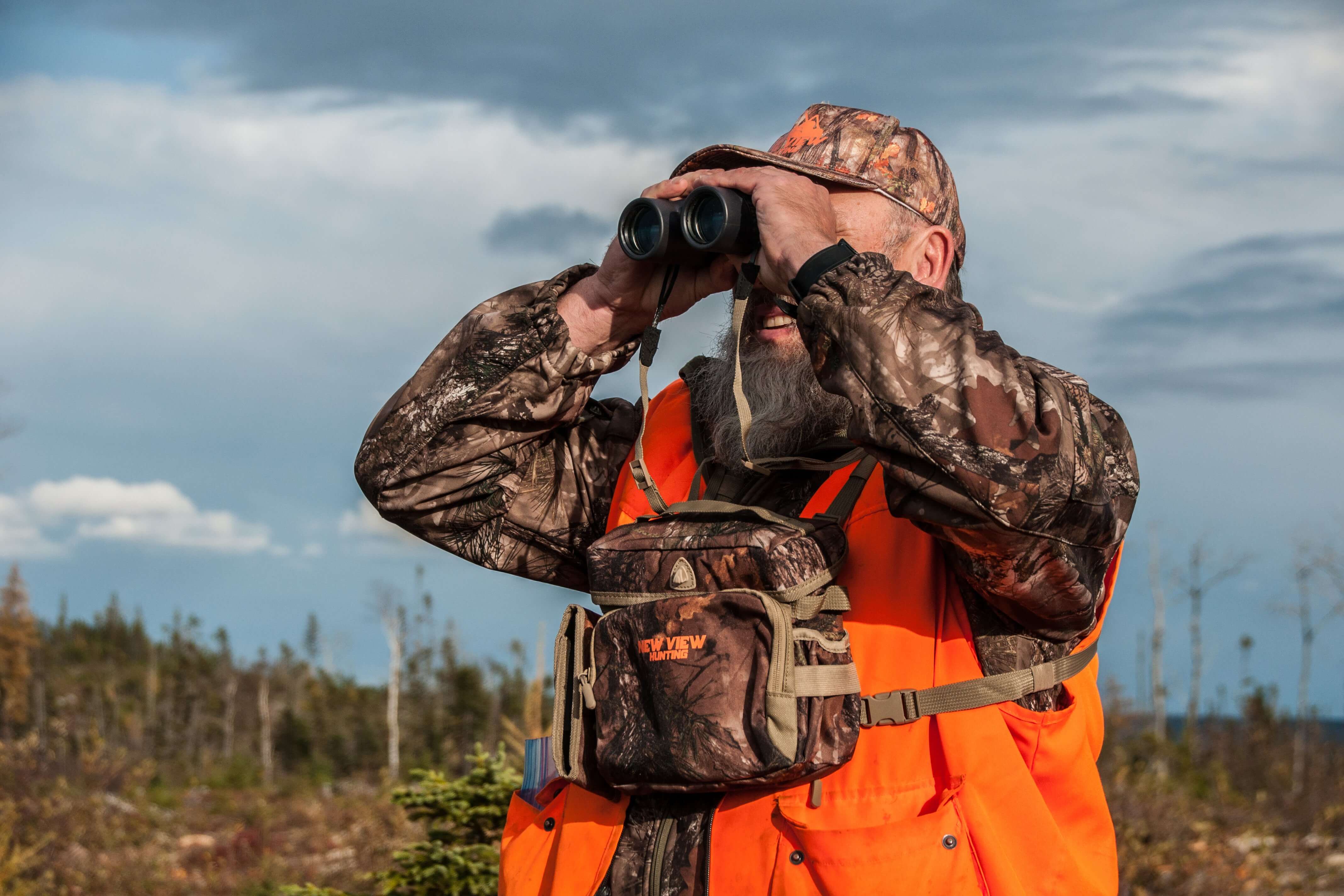 Hunter wearing a camo bino harness while glassing in the field