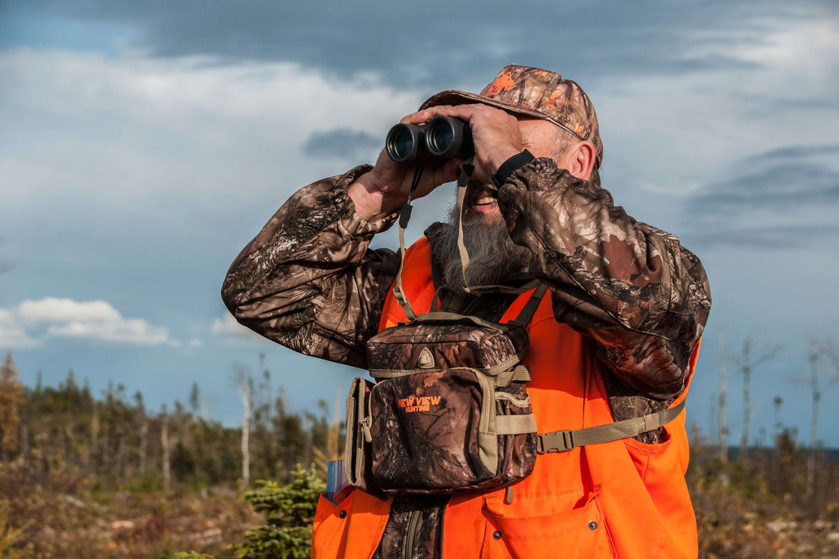 Hunter wearing a camo bino harness while glassing in the field