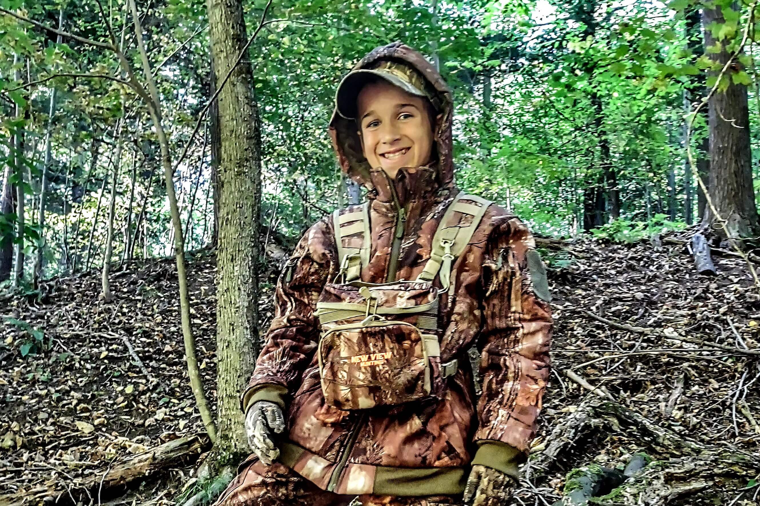 Young hunter wearing camouflage hunting clothing in woodland