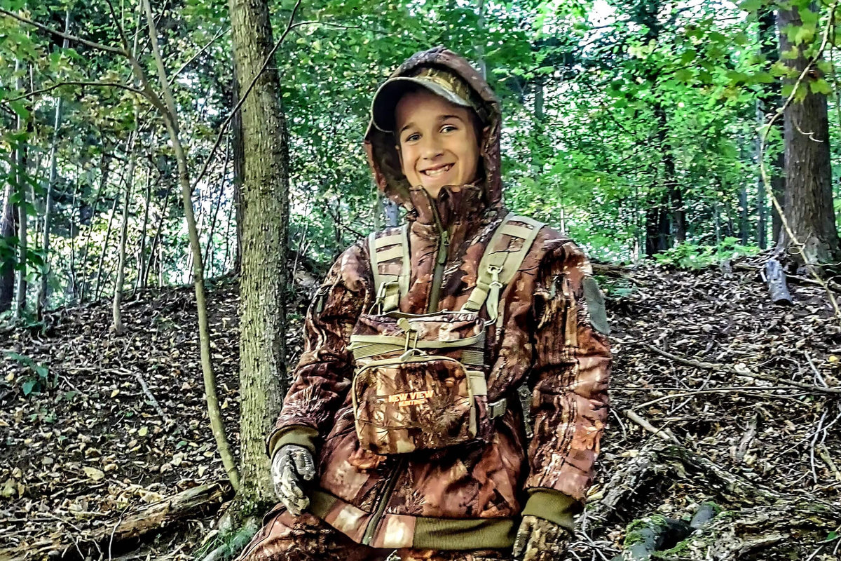 Young hunter wearing camouflage hunting clothing in woodland